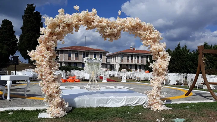 Çiçek kemerli açık alan nikah sahnesi ve düğün kurulumu
